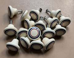 Set of 16 ceramic drawer pulls. Off white w-red & blue stripe w-back screws.