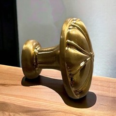 A cast zinc knob with a sunset motif, in a polished brass finish. Measures 1-1/4